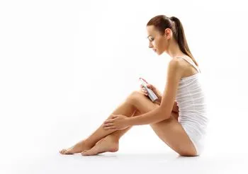 Kobieta wcierająca balsam w skórę nóg