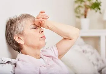 starsza kobieta trzyma dłoń na czole