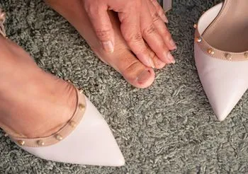 Wrastające paznokieć często powstaje jako efekt noszenia ciasnego obuwia o zwężających się czubkach, zwykle na wysokich obcasach. Fot. Adobe Stock.