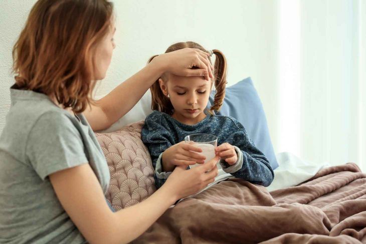 Kobieta podaje antybiotyk dziecku.