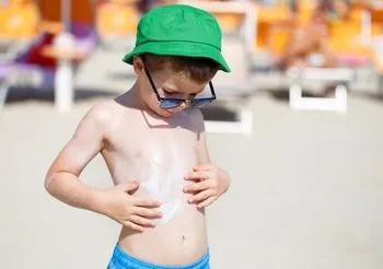 Chłopiec smaruje się kremem