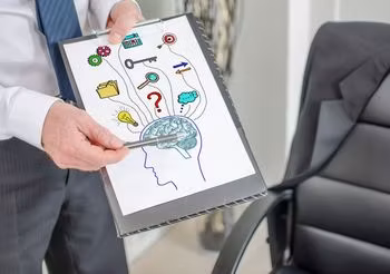 mężczyzna trzyma tablicę z rysunkiem przedstawiającym mózg