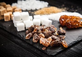 różne rodzaje cukru białego i brązoweho na ciemnym stole i podkładce