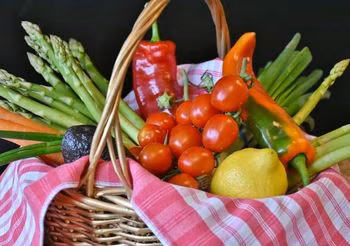 owoce i warzywa w koszu: pomidory, cytryna, papryki, szparagi