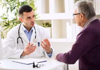 lekarz rozmawiający przy biurku z mężczyzną