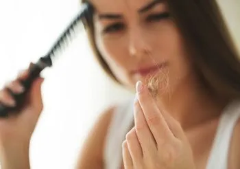 Kobieta trzyma kępkę włosów po czesaniu