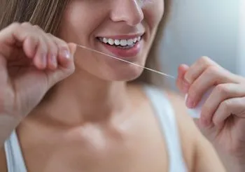 Zdjęcie przedstawia kobietę, która w prawidłowy sposób czyści zęby.