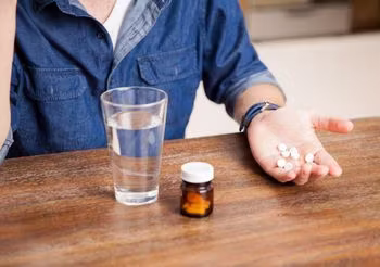 mężczyzna trzyma w garści tabletki