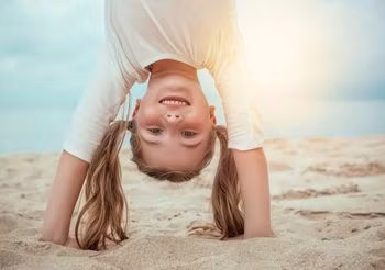 dziewczynka stoi na rękach na plaży