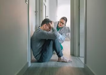 Chory z katatonią siedzi bez ruchu, pomaga mu psychiatra.