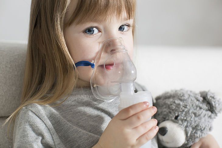 Kilkuletnia dziewczynka w masce nabulizatora podczas inhalacji.