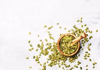 Pestki dyni w niewielkim moździeżu i rozsypane wokól niego 