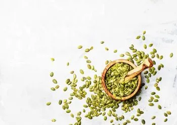 Pestki dyni w niewielkim moździeżu i rozsypane wokól niego 