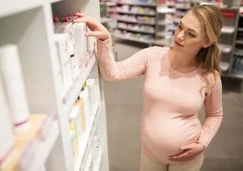 Kobieta w ciąży przeglądająca ofertę kosmetyków w aptece