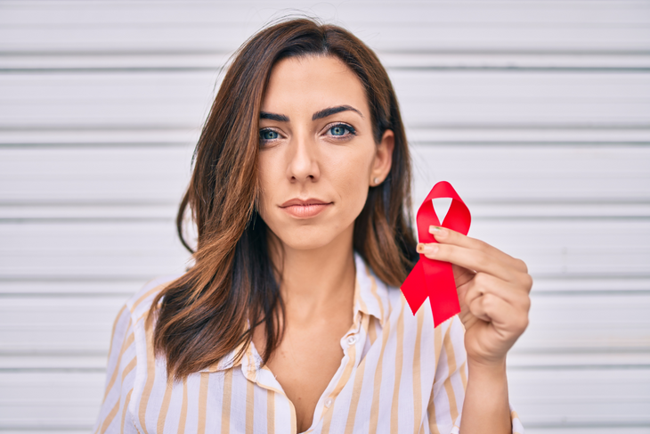 Czerwona wstążka to symbol solidarności z osobami chorymi na AIDS i zarażonymi wirusem HIV. Według WHO w 2021 r. wirusem zakaziło się 1,5 miliona ludzi, a w sumie zakażonych jest 38 milionów i 400 tysięcy osób. Fot. Adobe Stock.