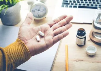 Mężczyzna trzymający w dłoni tabletki