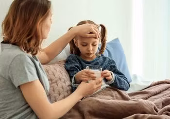 Kobieta podaje antybiotyk dziecku. 