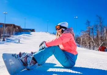 Młoda snowboardzistka odpoczywa na stoku