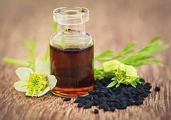 kwiat i nasiona czarnuszki oraz olej z czarnuszki w szklanym flakonie
