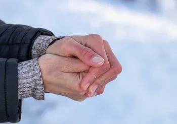 Zmarznięte dłonie na tle śniegu. 