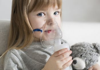 Kilkuletnia dziewczynka w masce nabulizatora podczas inhalacji.