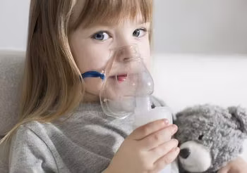 Kilkuletnia dziewczynka w masce nabulizatora podczas inhalacji. 