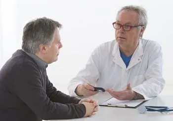 starszy mężczyzna siedzi przy stole w gabinecie lekarskim