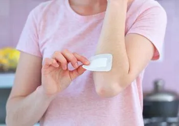 Kobieta nakłada opatrunek ze srebrem koloidalnym na skórę ręki.