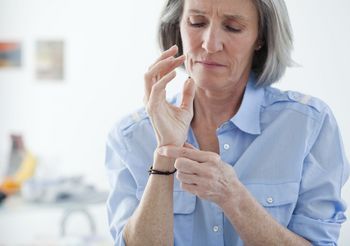 Starsza kobieta ogląda swoje nadgarstki