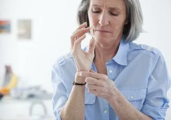 Starsza kobieta ogląda swoje nadgarstki 