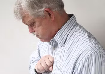 starszy mężczyzna trzyma się za klatkę piersiową