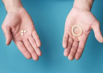 Dłonie z prezerwatywą i pigułkami