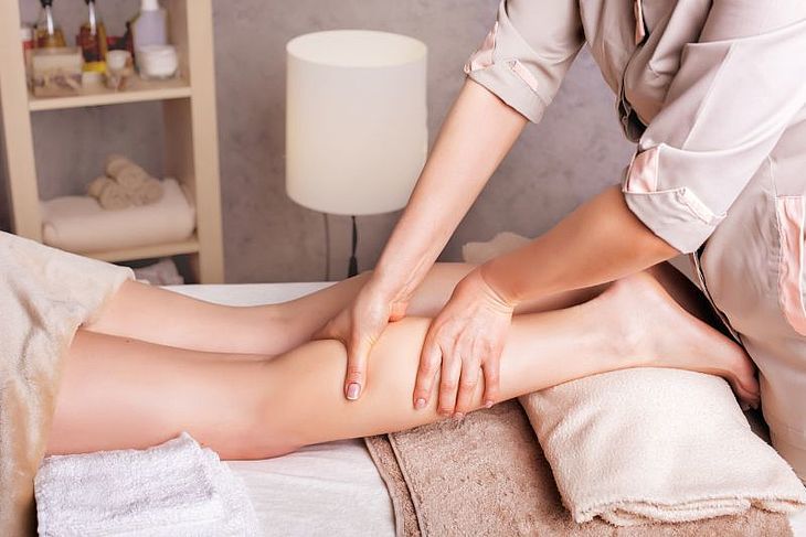 pracownik salonu masażu masuje nogę pacjentki